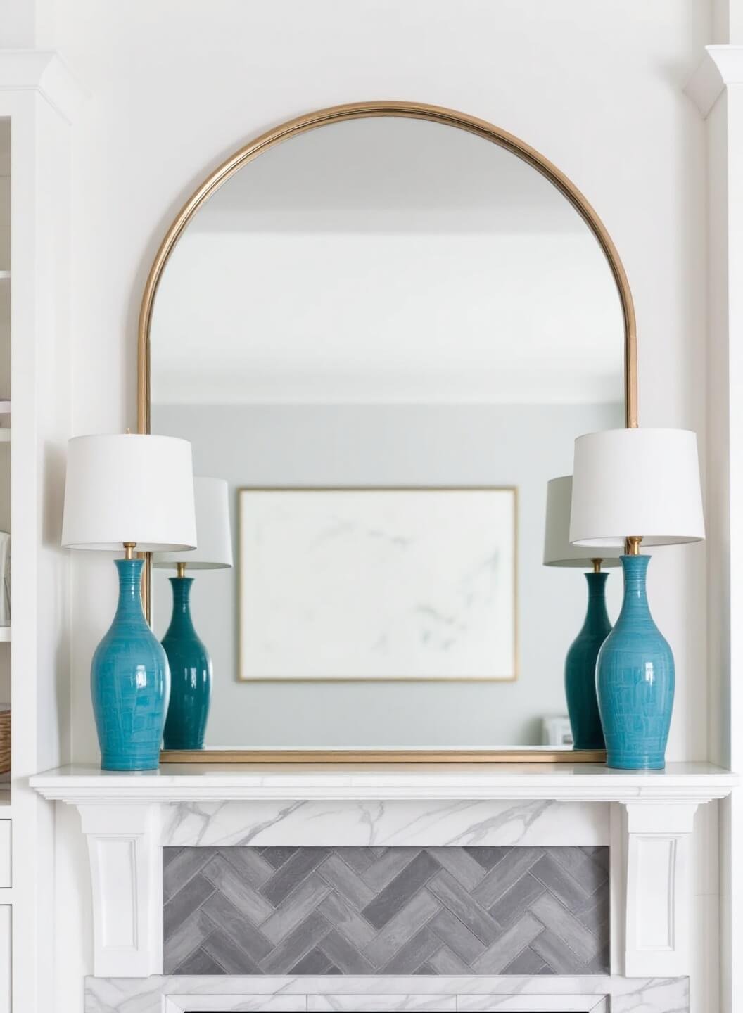 Transitional fireplace wall featuring oversized arched mirror, built-ins, herringbone marble surround and ceramic lamps, shot under soft midday light