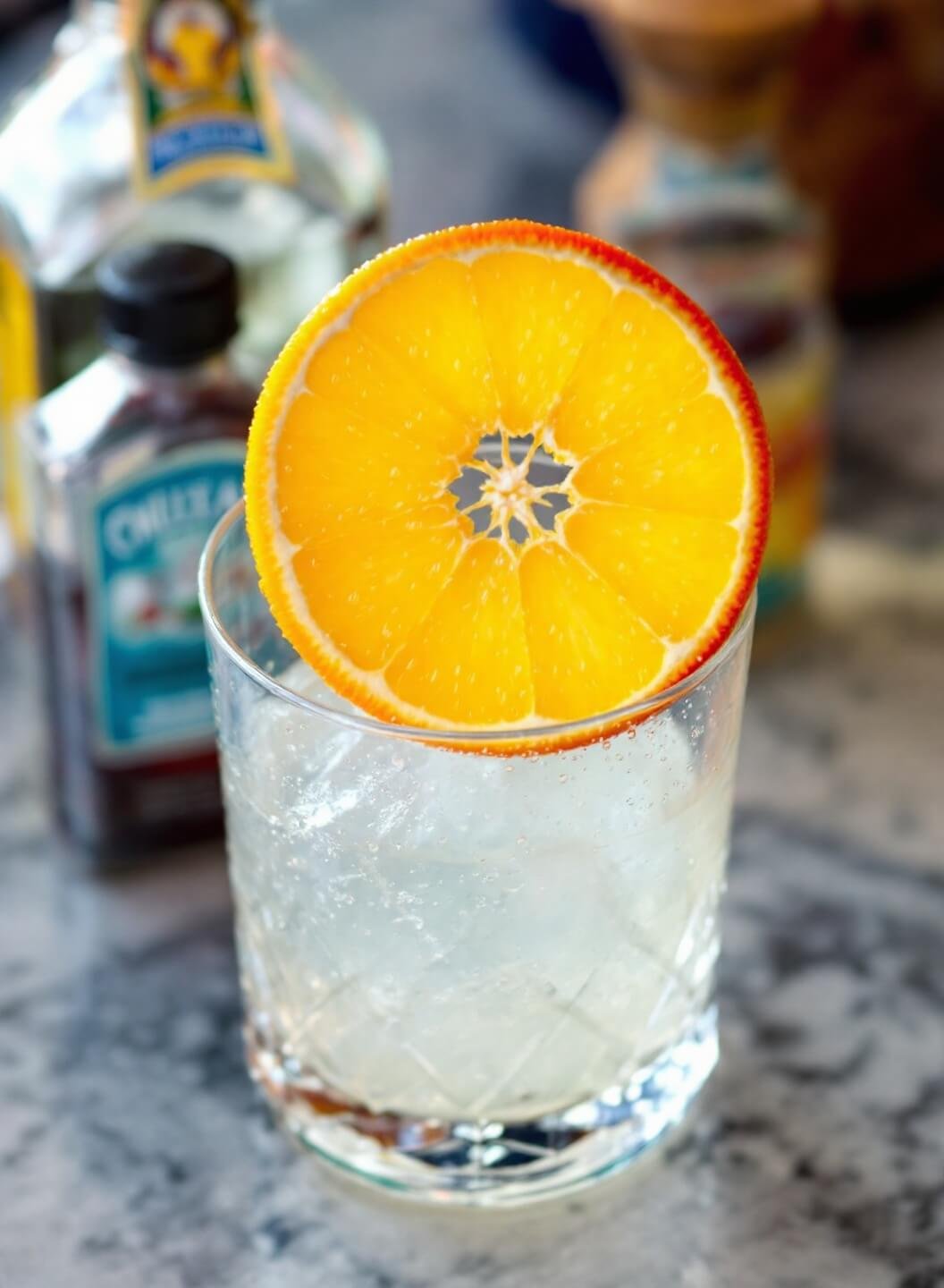 Orange slice garnish on glass rim in blurred bar setting