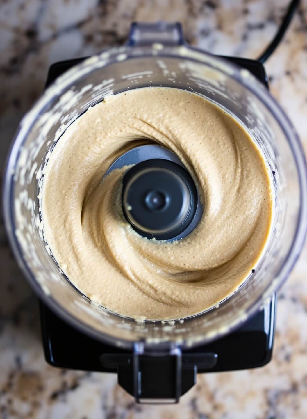 Blending chickpeas and tahini in a food processor for hummus preparation