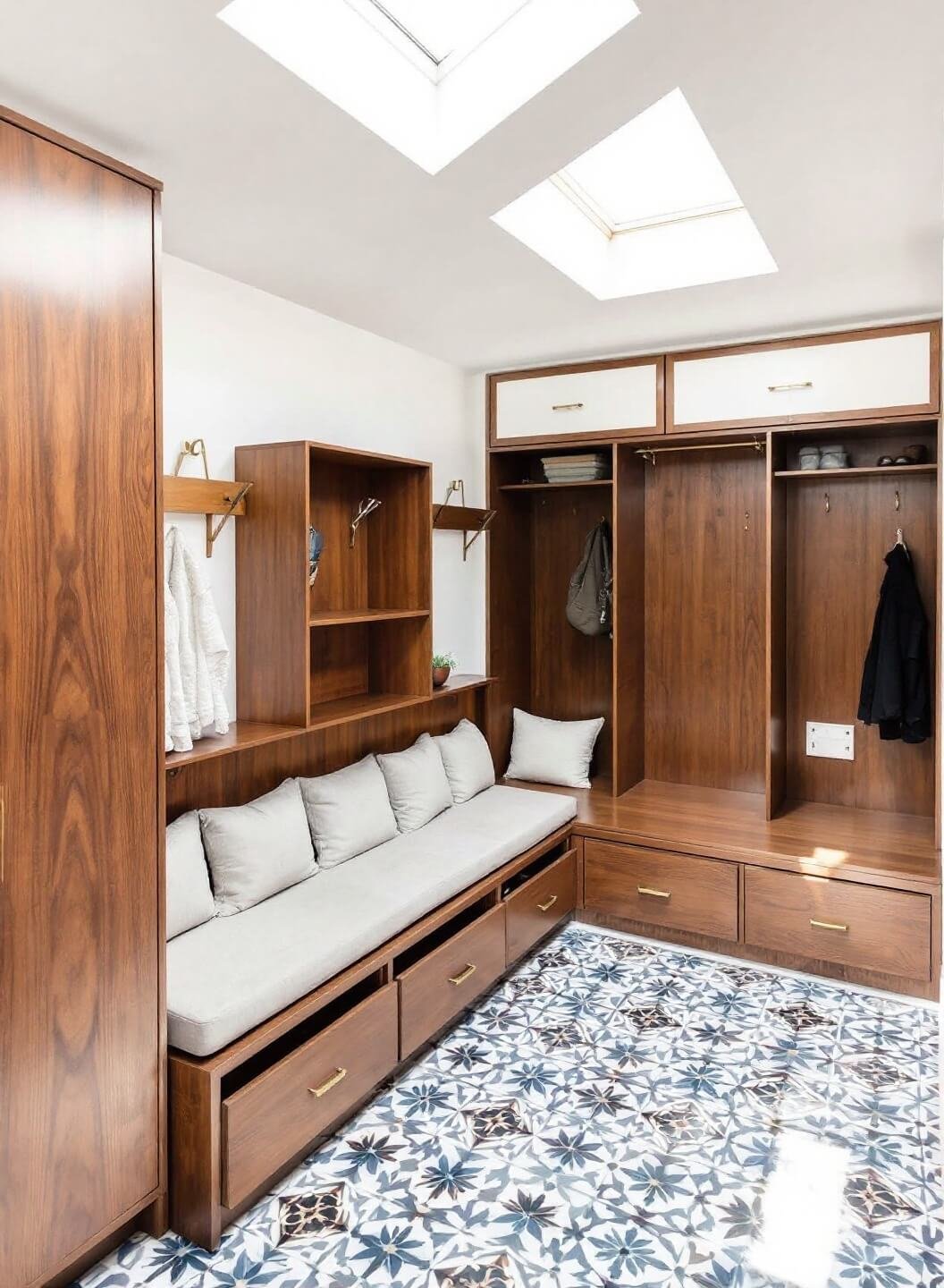 Bird's eye view of an organized entryway featuring walnut L-shaped bench with hidden shoe drawers and linen cushions, custom built-in storage, geometric cement tile flooring and natural overhead light from skylight