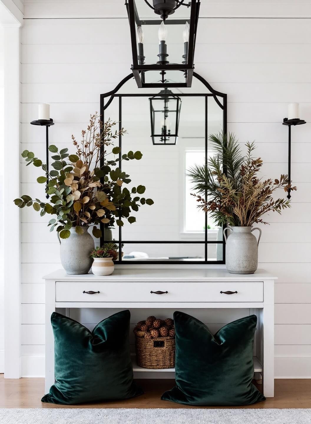 Modern farmhouse entryway at dusk with shiplap detail, black metal-framed mirror, whitewashed console, natural elements in vintage pottery, soft iron chandelier lighting, forest green velvet pillows, and neutral walls shot through a wide-angle lens.