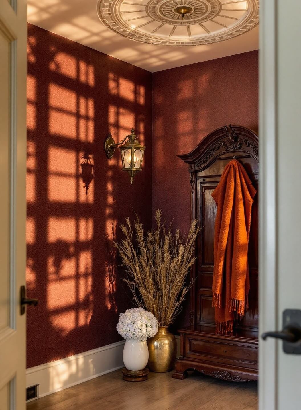 Victorian entryway corner at magic hour featuring a brass lantern, carved mahogany hall tree with wool scarf, and autumnal decorations including white ceramic pumpkins and dried hydrangeas in copper vessels